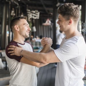 two-happy-young-male-friends-shaking-hands-restaurant(1)
